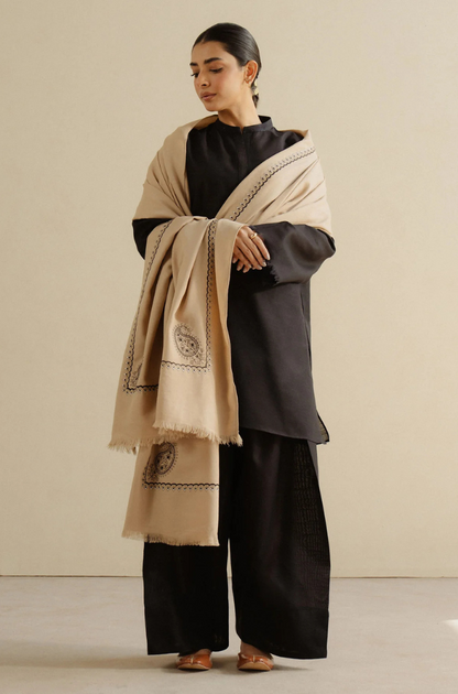 A woman wearing a chic black and beige shawl, highlighting her refined taste in accessories.