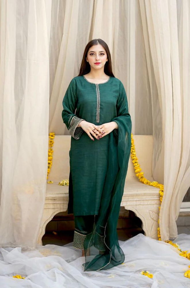 A woman dressed in a vibrant green Pakistani suit, highlighting cultural fashion and graceful elegance.