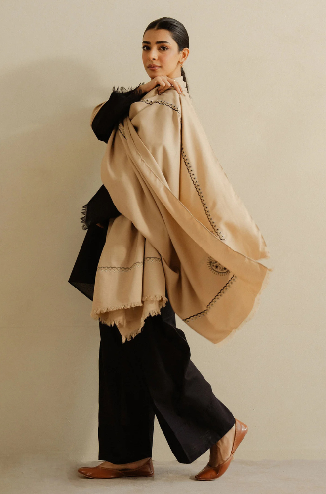 A woman draped in a stylish black and beige shawl, exuding elegance and sophistication.