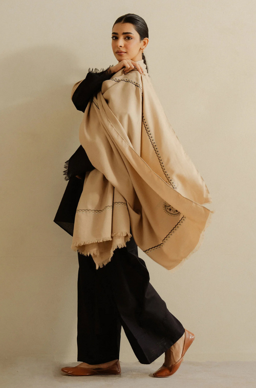 A woman draped in a stylish black and beige shawl, exuding elegance and sophistication.