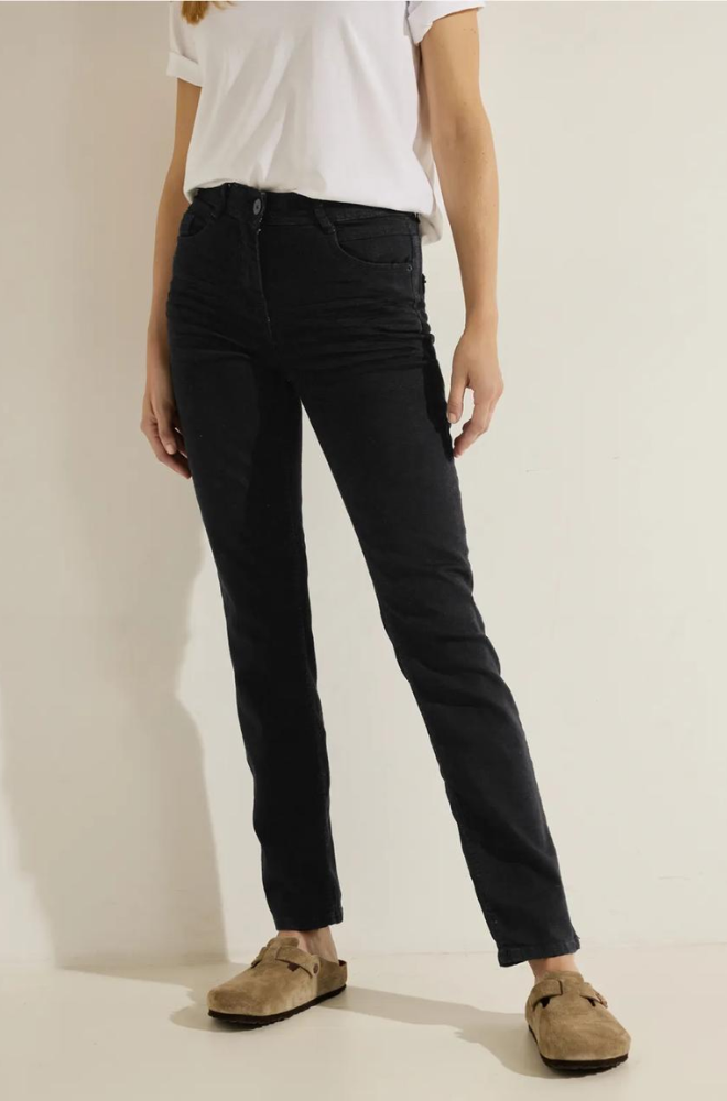 A woman in black jeans and a white t-shirt poses, embodying a relaxed and fashionable look suitable for everyday wear.
