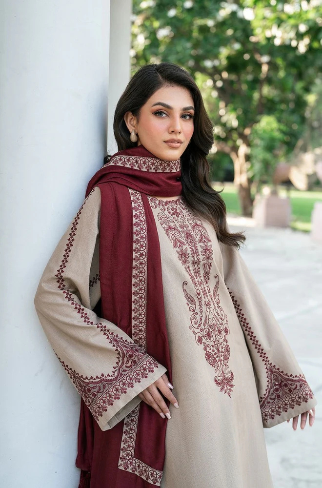 A woman wearing a stylish beige and maroon suit, exuding confidence and elegance in her attire.