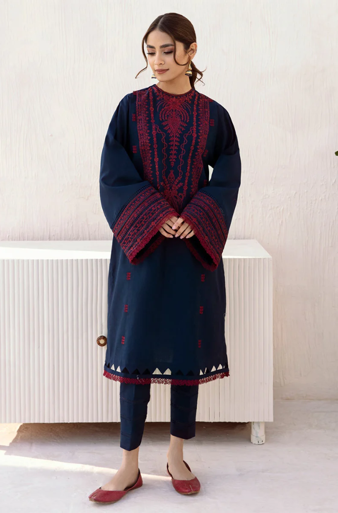 The model showcases a navy blue kurta suit featuring detailed red embroidery, exemplifying a blend of tradition and modern fashion.
