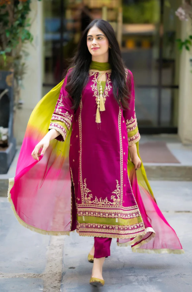 A woman in a pink and green suit confidently walks down a city street, surrounded by urban scenery.