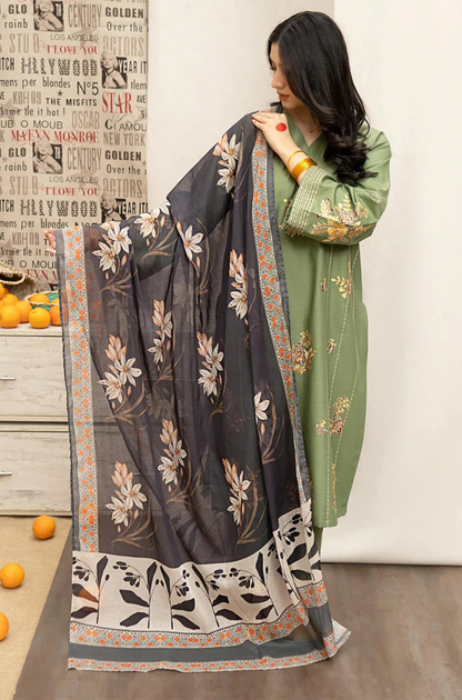 A woman wearing a green and white dress adorned with intricate floral embroidery stands gracefully.