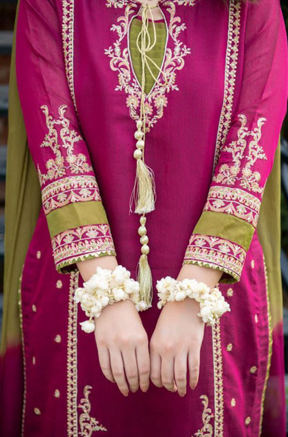 A woman in a pink and green suit highlighting her fashionable attire against an urban backdrop.