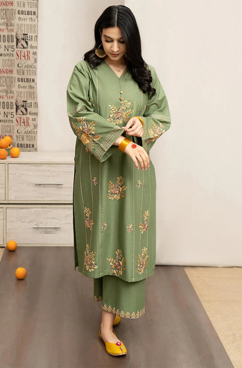  A woman wearing a green kurta suit paired with matching pants, standing gracefully in a serene setting.
