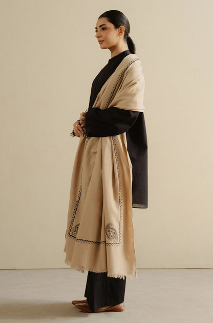 A woman elegantly adorned in a black and beige shawl, showcasing a blend of classic and contemporary fashion.
