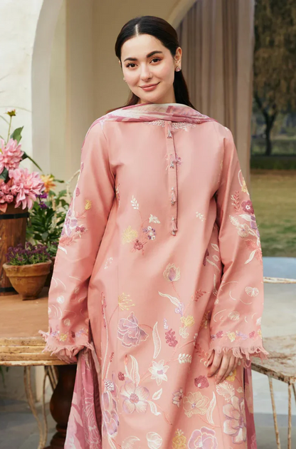 A woman in a pink and white embroidered suit, exuding elegance and style with detailed floral patterns.
