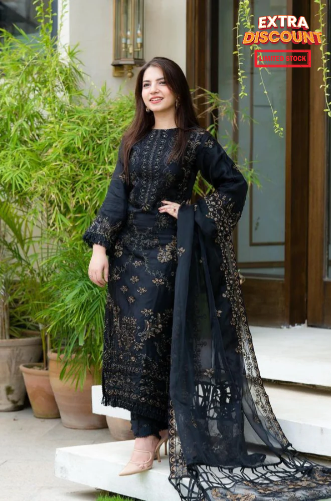  A woman stands confidently for the camera, adorned in a striking black and gold dress that accentuates her style.