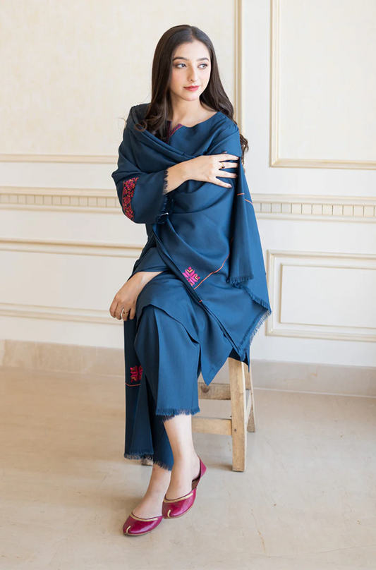 A woman in a blue dress seated gracefully on a chair, exuding elegance and poise.