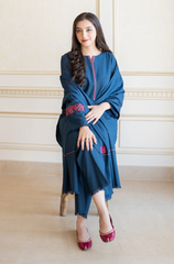  A woman wearing a blue dress sits on a chair, showcasing a serene and composed demeanor.